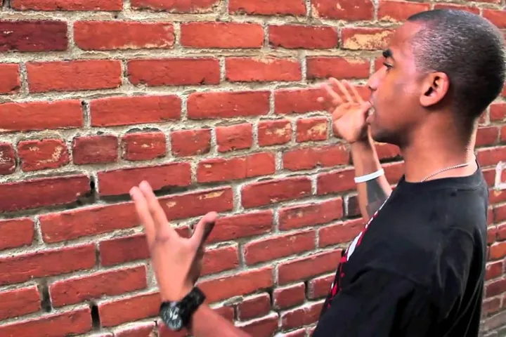 Un homme parle à un mur de briques