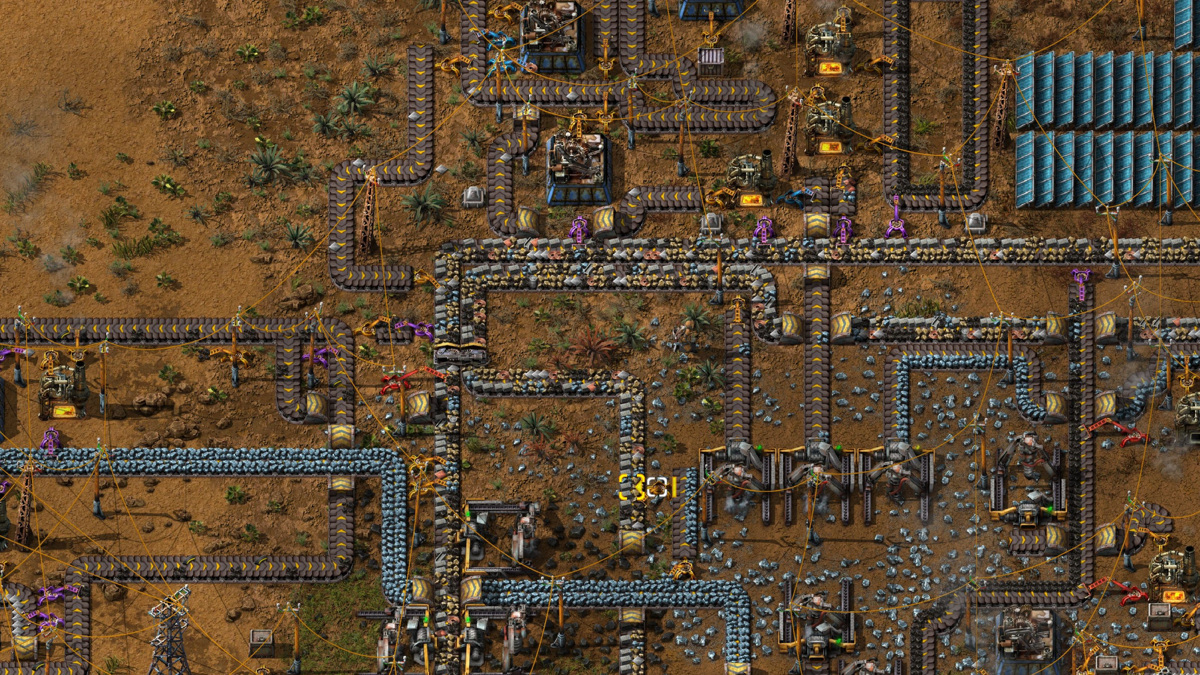 Vue aérienne d'une usine dans Factorio, avec tapis roulants, bras robotisés et panneaux solaires sur un sol désertique