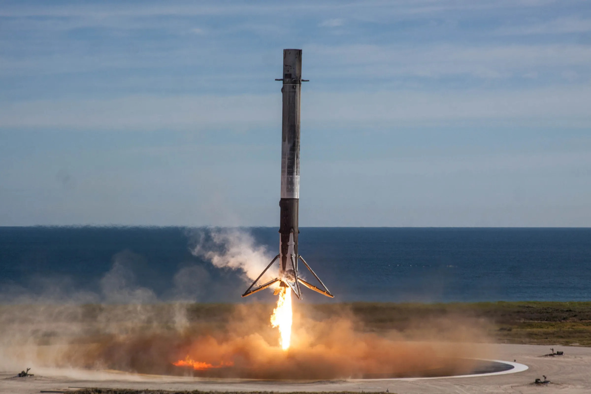 Premier étage de fusée Falcon 9 atterrissant verticalement, train déployé et moteur allumé, près de l'océan