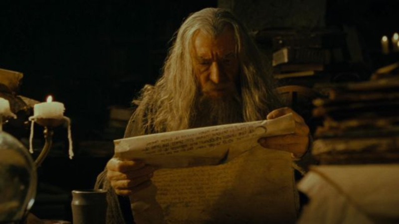 Gandalf lit un vieux parchemin à la lueur d'une bougie dans une pièce encombrée de livres, scène du Seigneur des anneaux
