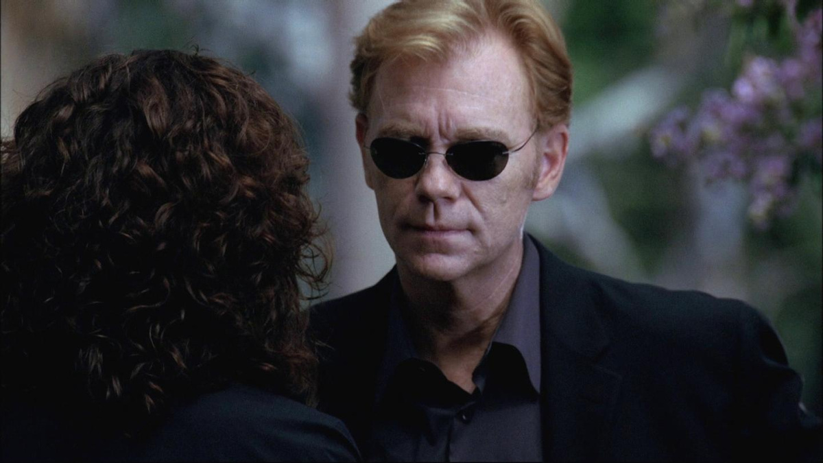 Horatio Caine des Experts Miami, lunettes noires et mine impassible, face à un interlocuteur