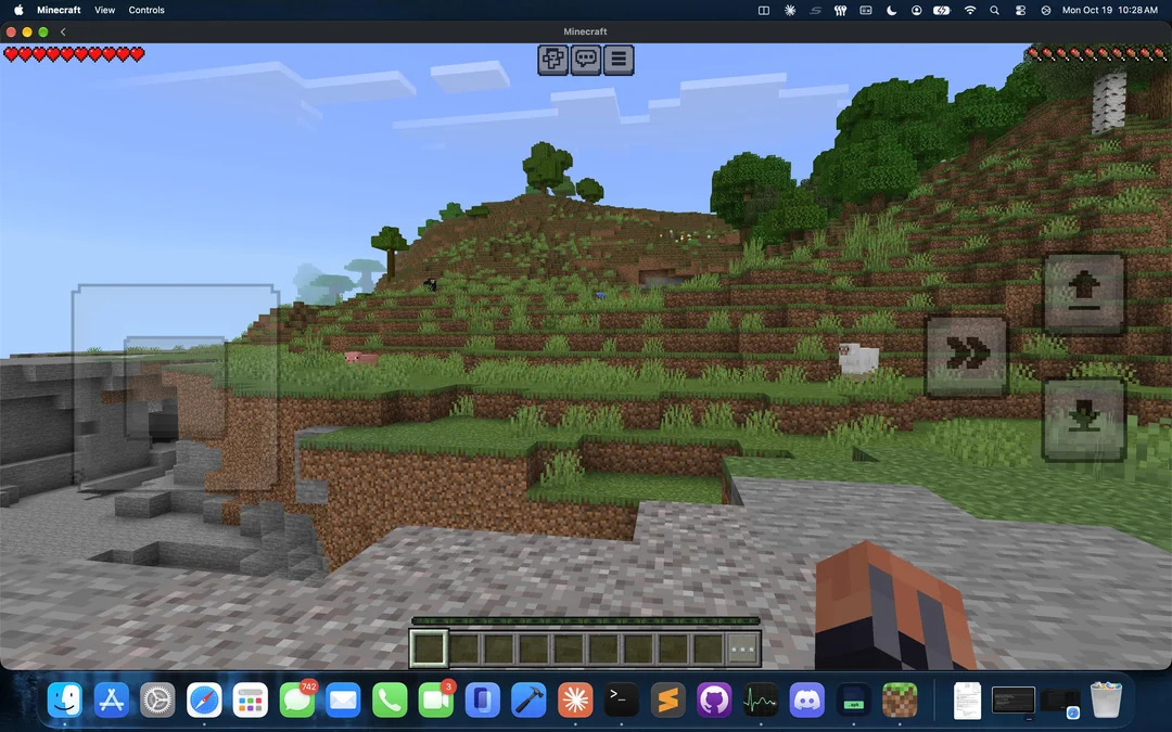 Minecraft Android lancé dans une fenêtre sur macOS, avec commandes tactiles à l'écran et paysage de collines herbeuses