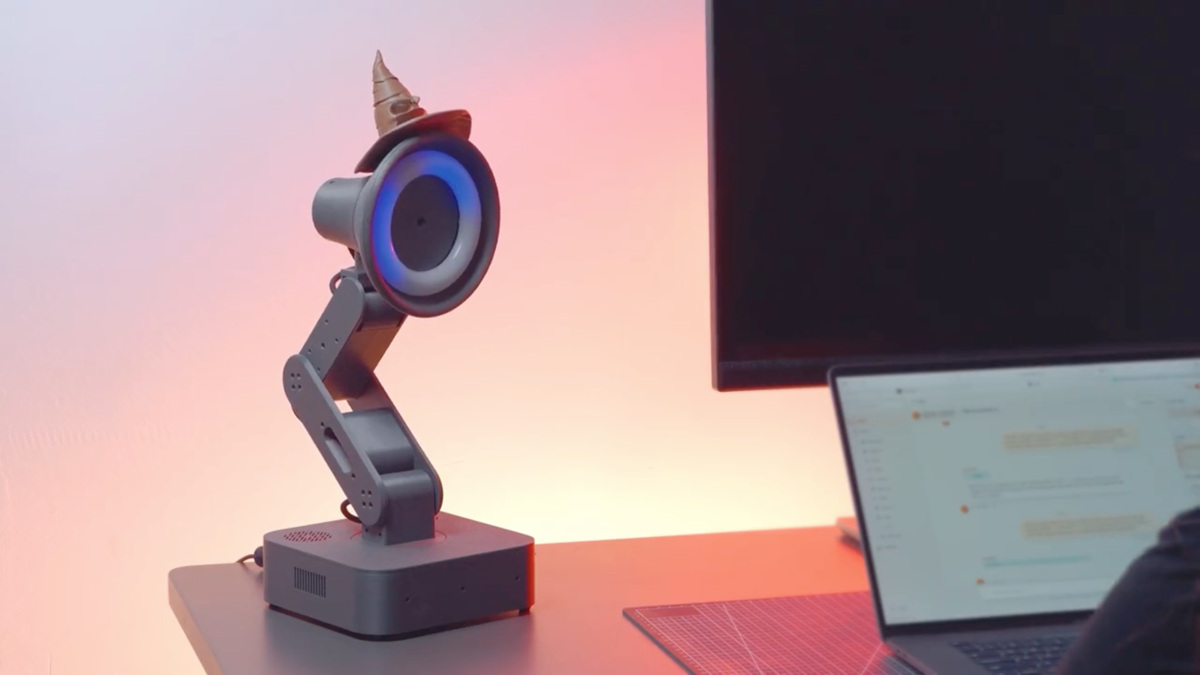 Robot de bureau Lamp, lampe articulée à anneau bleu lumineux, coiffé d'un Choixpeau magique, posé devant un laptop