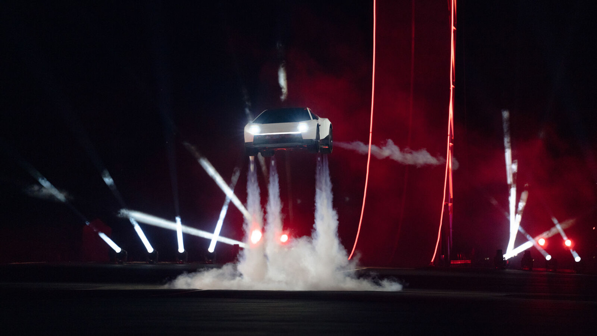 Tesla Roadster décollant du sol grâce à ses propulseurs, fumée blanche et lumières rouges nocturnes